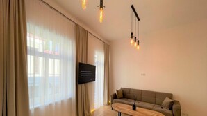 A modern living room with a sofa, a coffee table, and a TV mounted on the wall. - Picturesque Old Town Apartment With Balcony (Kaunas)