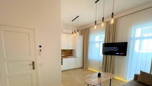 A modern living room with a sofa, a coffee table, and a TV mounted on the wall. - Picturesque Old Town Apartment With Balcony (Kaunas)