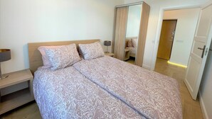 A bedroom with a bed, bedside tables, a mirror, and a wardrobe. - Picturesque Old Town Apartment With Balcony (Kaunas)