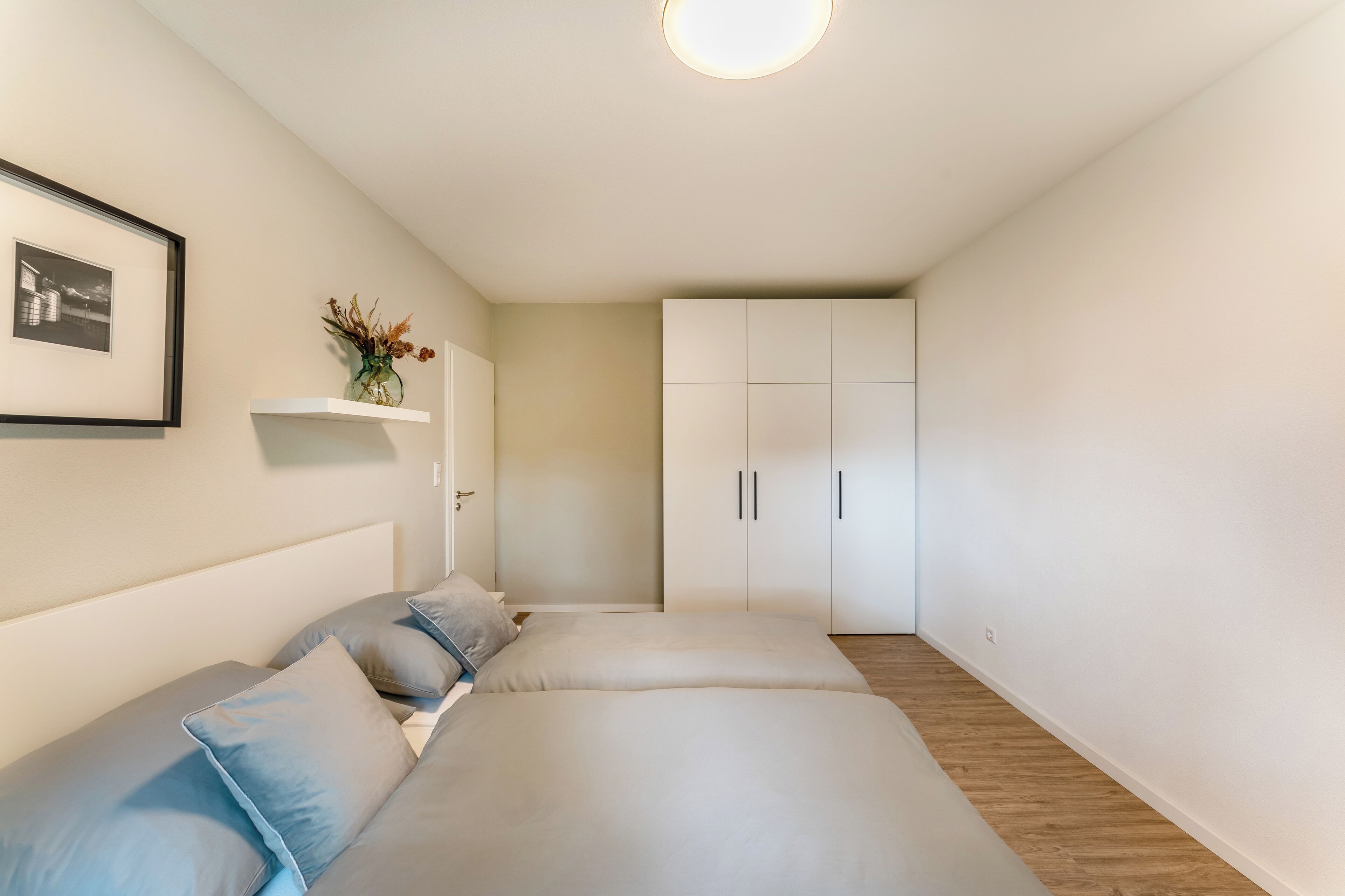 Ein Schlafzimmer mit einem Bett, einem Nachttisch, einem gerahmten Bild und einem Kleiderschrank.