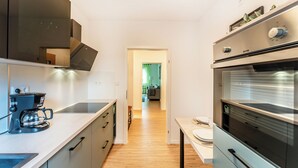 A modern kitchen with a coffee maker, oven, and cabinets. - City-Luxury Apartment Rottweil (Rottweil)
