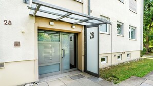 A modern building with a glass door entrance, a number '28' sign, and a small garden area. - City-Luxury Apartment Rottweil (Rottweil)