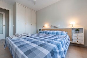 A bedroom with a bed, a wardrobe, a bedside table, and a lamp.