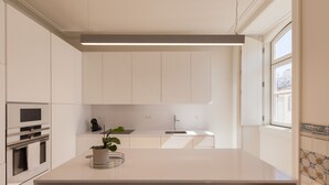 Una cocina moderna con armarios blancos, horno empotrado y una isla grande con una planta.