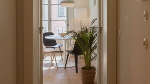 Un pasillo que conduce a un comedor con una mesa, sillas y una planta en maceta.