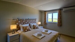 A neatly arranged bedroom with a large bed, two bedside tables, and a window with curtains. - FLH Quinta das Salinas Triplex with Terrace & Pool (Vale do Lobo)