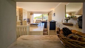 A modern kitchen with a central island, a dining area with a sofa, and a view of the outdoors. - FLH Quinta das Salinas Triplex with Terrace & Pool (Vale do Lobo)