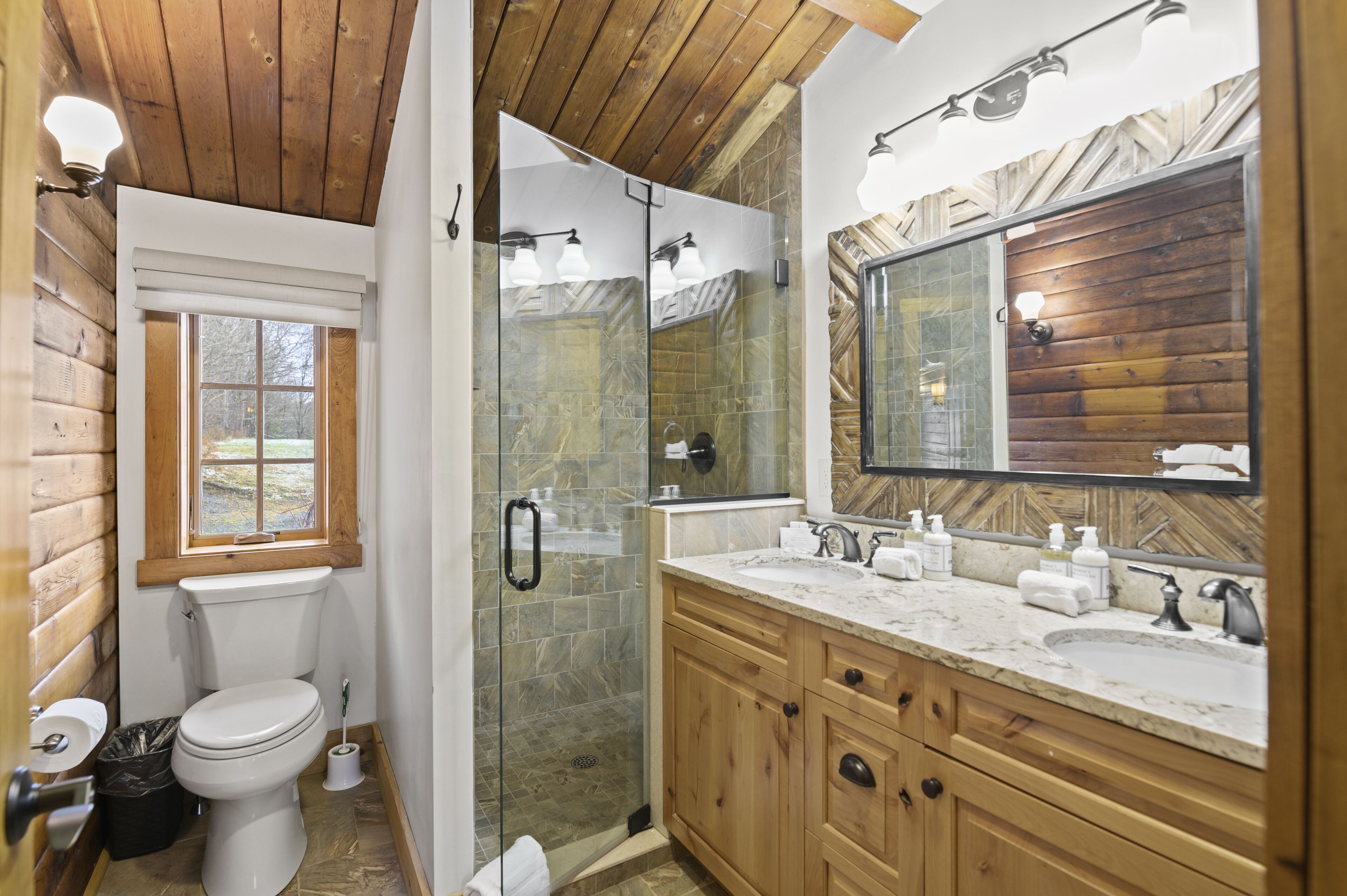 A bathroom with a toilet, shower, and vanity with a large mirror.