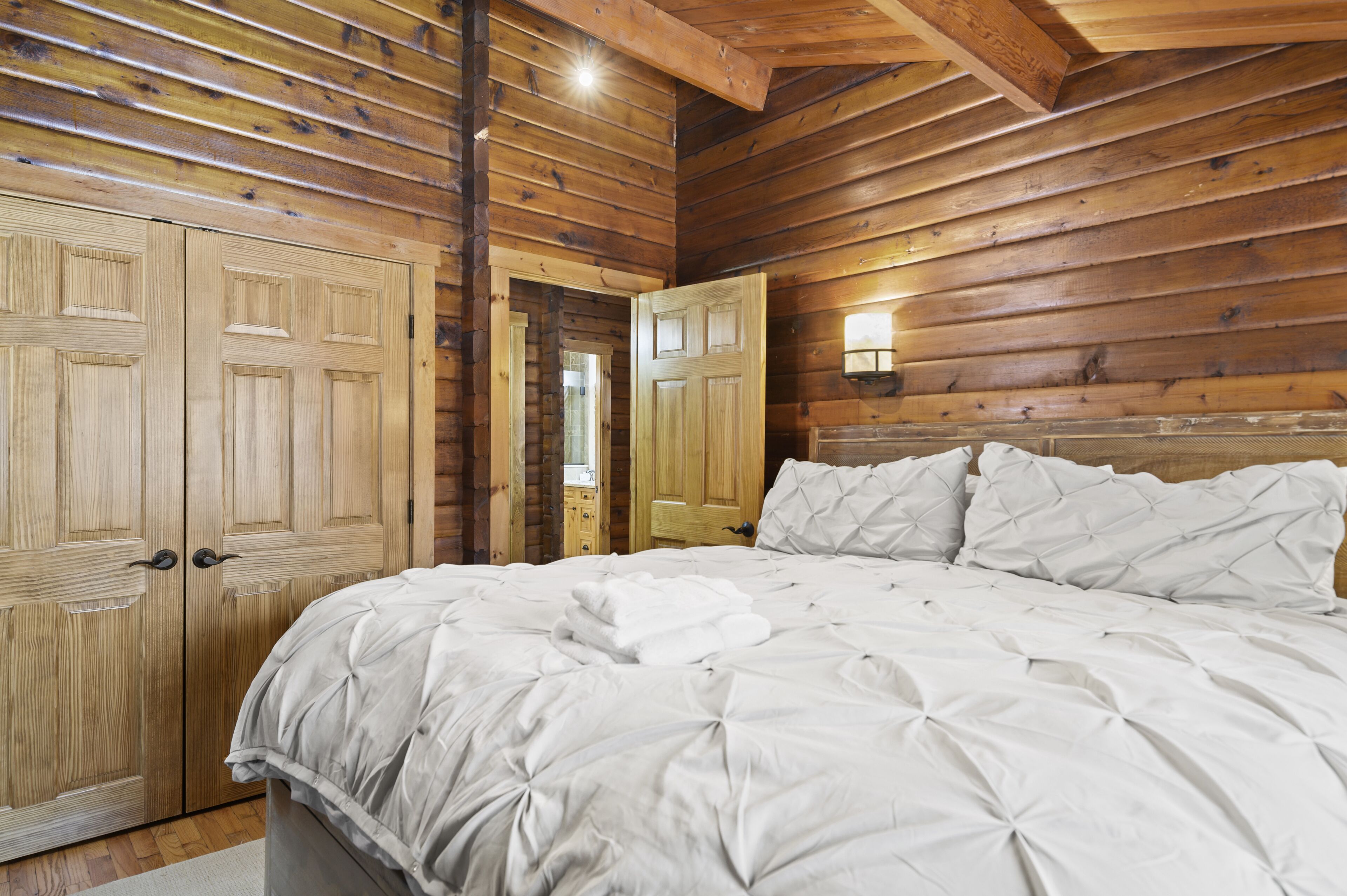 Un dormitorio con una cama grande, paredes de madera y techo de madera.