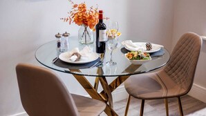 A round glass table with a wine bottle, glasses, and plates of food. - Modern & Mellow 1-bed Apt w/ Free Parking & Wi-Fi (Bournemouth)