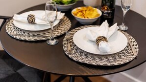 A dining table set with plates, napkins, cutlery, and a bottle of champagne. - Cosy, Beautiful Studio Apt w/ Free Parking & Wi-Fi (Bournemouth)