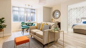 Una sala moderna con sofá, reposapiés y un comedor con mesa y sillas.