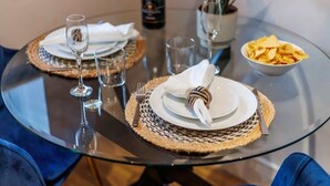 A dining table set with plates, cutlery, and glasses, with a bottle and a bowl of chips on the table. - Simply Beautiful 1-bed Apt w/ Free Parking & WiFi (Bournemouth)