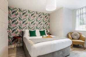 A bedroom with a bed, green pillows, a side table, a chair, and a window with blinds. - Spacious, Beautiful 1-Bed Apt; Central, Wi-Fi, PKG (Bournemouth)