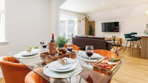 Ein moderner Essbereich mit einem Glastisch, gedeckt für eine Mahlzeit, umgeben von orangefarbenen Stühlen.
