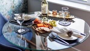 Ett glasbord med en vinflaska, vinglas och ett urval av snacks.