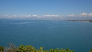 Paisagem costeira com vista clara para o mar e montanhas ao longe.