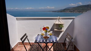 Varanda com mesa posta para o café da manhã, com vista para a costa.