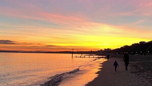 En strand ved solnedgang med en pille der stikker ud i vandet.