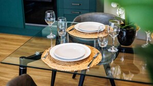 Una mesa de comedor dispuesta con platos, vasos y una planta en maceta.