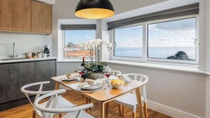 Una cocina moderna con comedor, ventanas amplias con vistas e iluminación colgante.