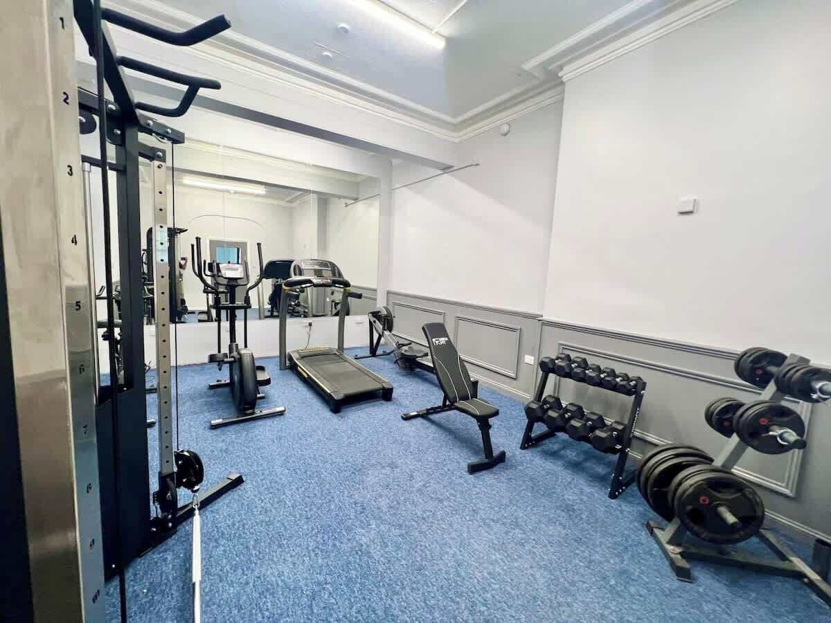 A gym with exercise equipment, a treadmill, and dumbbells.