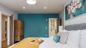 A bedroom with a bed, a breakfast tray, a wardrobe, and a painting on the wall. - Spacious Garden, 2-Bed Apt w/ Free Gym & Parking (Bournemouth)