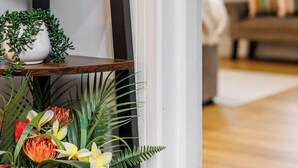 A wooden ladder shelf with decorative items including a bowl, a small white pot, and a floral arrangement.