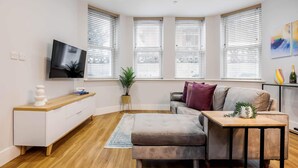 A modern living room with a sofa, a coffee table, a TV, and a plant.