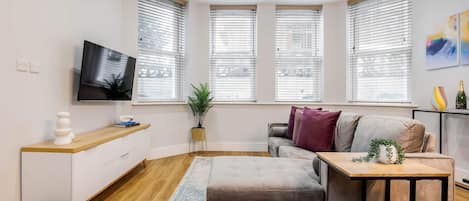 A modern living room with a sofa, a coffee table, a TV, and a plant.