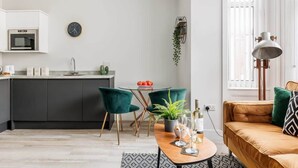 A modern kitchen with a microwave, a sink, and a dining area with a table, chairs, and a plant.