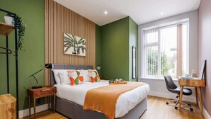 A bedroom with a bed, bedside tables, a desk, and a window.