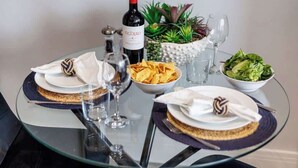 Une table en verre avec une bouteille de vin, des assiettes de nourriture et des verres.