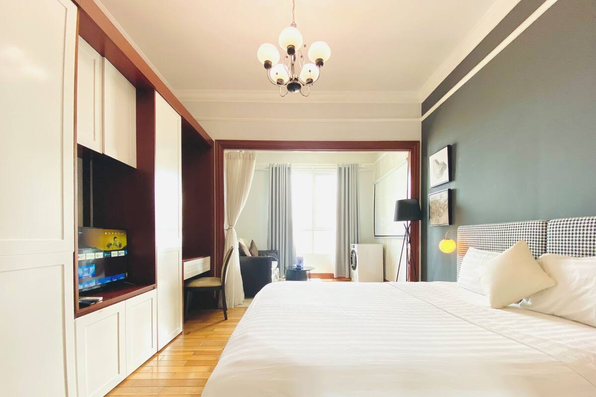 A hotel room with a large bed, a television, a desk, and a wardrobe.