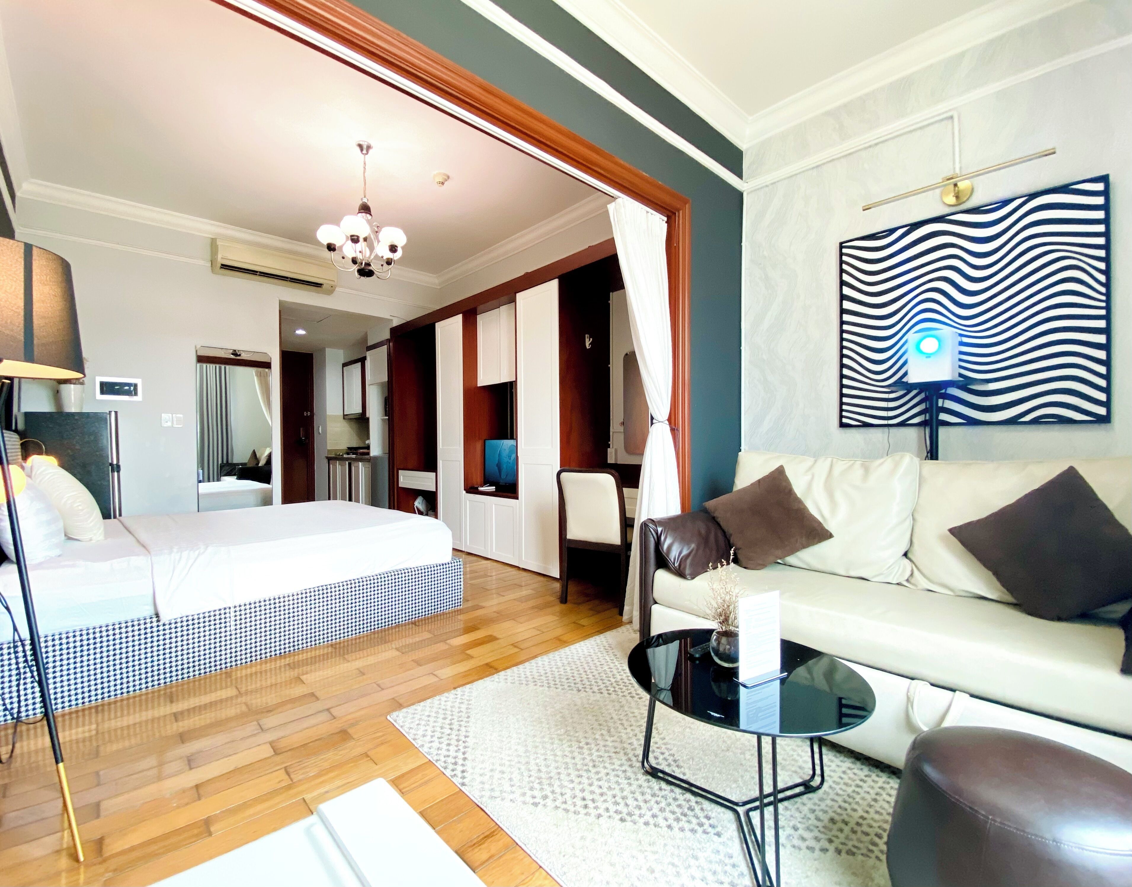A modern hotel room with a bed, a sofa, a coffee table, and a TV.