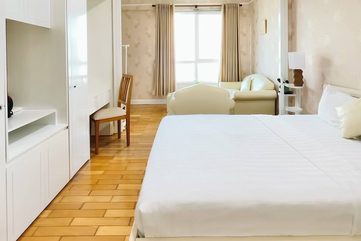 A hotel room with a bed, a chair, a desk, and a wardrobe.