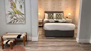 A modern bedroom with a bed, bedside tables, and a painting of birds on the wall. - Spacious 1-bed Studio Apt w/ Free Parking & WiFi (Bournemouth)