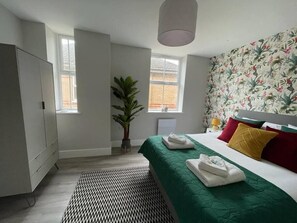 Una habitación de hotel con una cama, un armario, una planta en maceta y una ventana.
