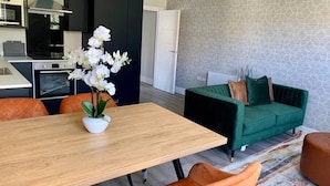 A modern kitchen with black cabinets, a wooden dining table, and a green sofa. - NEW & Vibrant 1-Bed in Town Centre w/ Free Parking (Bournemouth)