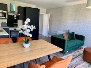 Una cocina moderna con armarios negros, una mesa de comedor de madera y un sofá verde.