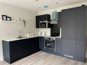 A modern kitchen with dark cabinetry, a built-in microwave, and an oven.