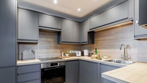 A modern kitchen with grey cabinets, a built-in oven, and a sink. - Wholesome Family 3-Bed, 2-Bath Apt; Free Gym & PKG (Bournemouth)