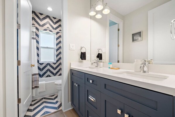 Un baño moderno con un tocador amplio, lavamanos dobles y un espejo.
