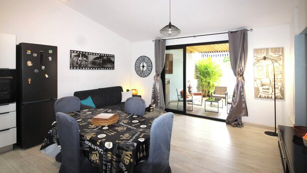 Una cocina moderna con comedor, un refrigerador negro y una mesa de comedor con sillas.