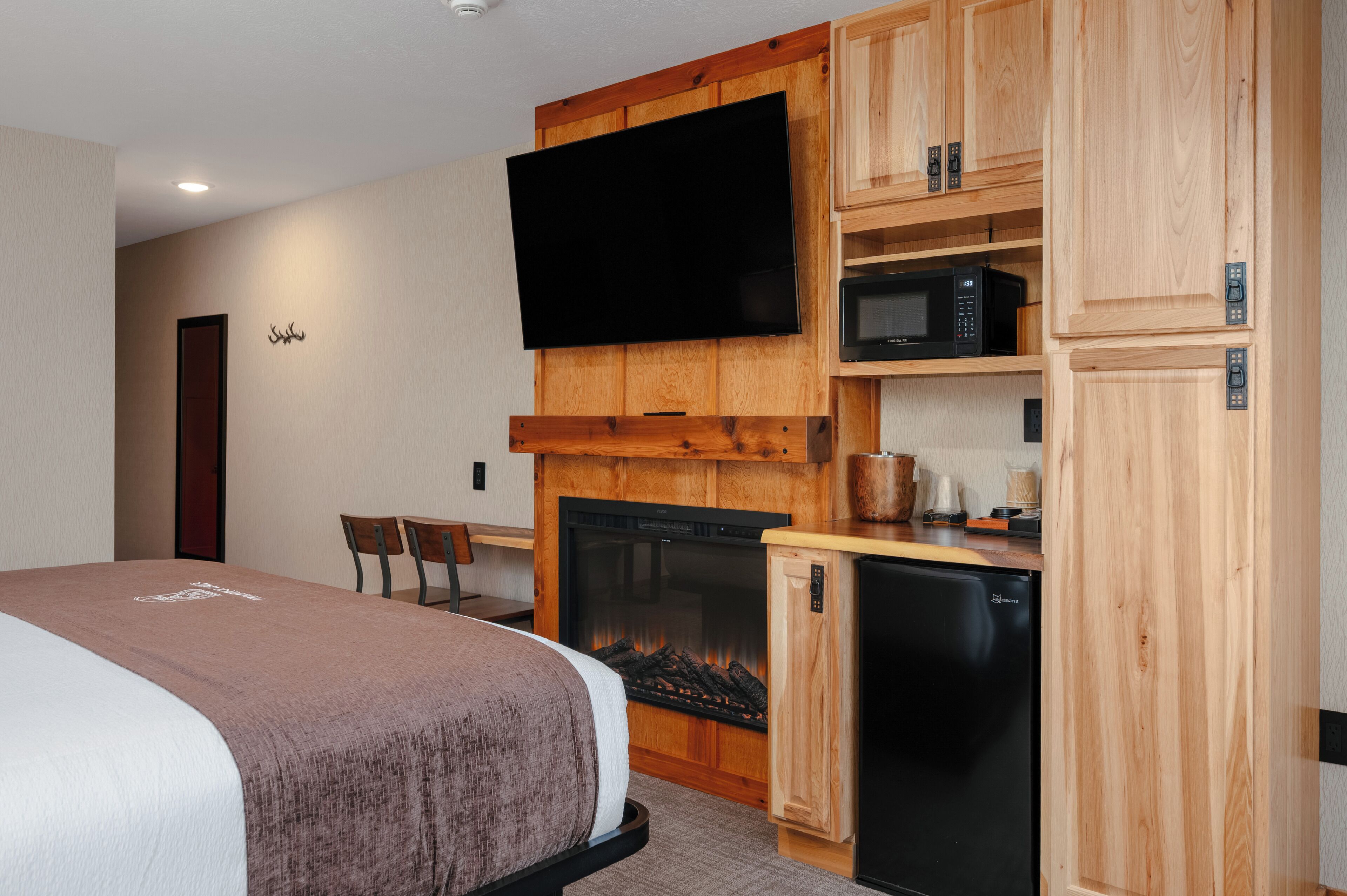 Habitación de hotel con cama, chimenea, televisor, microondas y refrigerador.