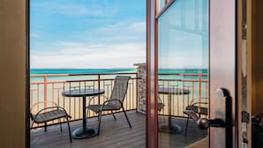A balcony with a view of the ocean, furnished with two tables and four chairs. - Tamarack Lodge of Traverse City (Traverse City)