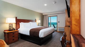 A hotel room with a bed, bedside tables, a desk, a chair, and a TV mounted on the wall.