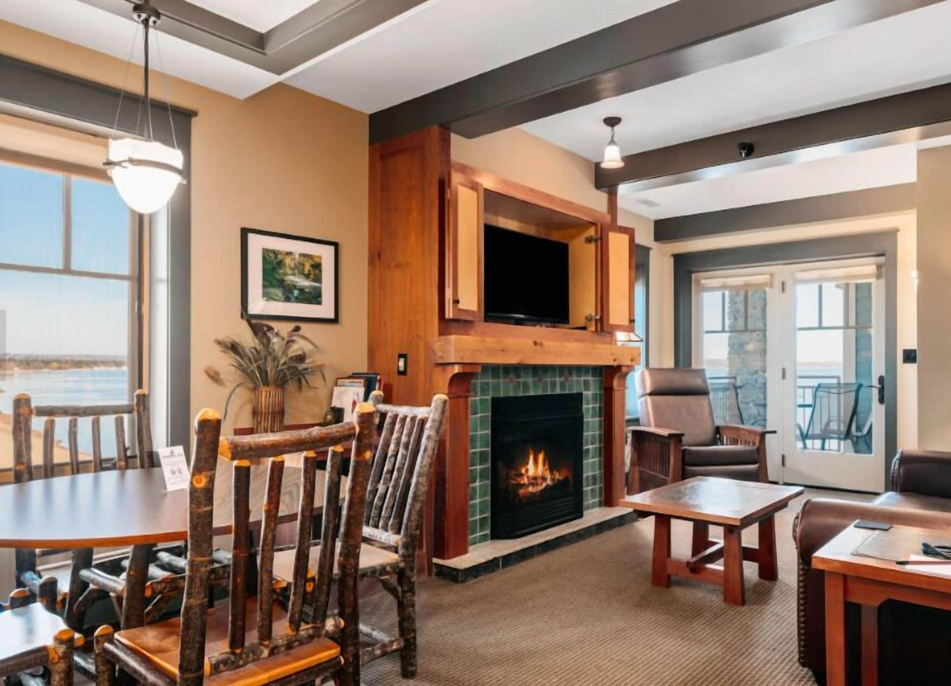 A cozy living room with a fireplace, a dining area, and a view of the outdoors.