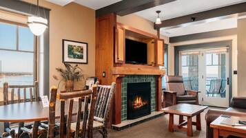 A cozy living room with a fireplace, a dining area, and a view of the outdoors.