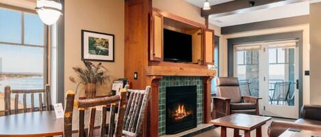A cozy living room with a fireplace, a dining area, and a view of the outdoors.
